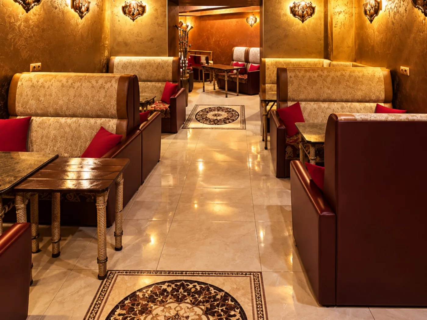 Cream damask booths with red cushions, gold sconces and a private alcove